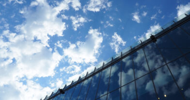 The sky and glass facade of the building. Reflection of the blue sky and white clouds on the glass wall. City skyscrapers. Modern glass buildings and architecture.